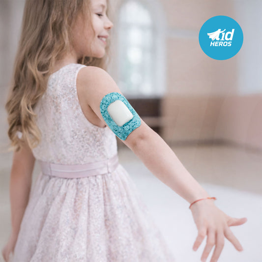 Child wearing a medical device on their arm with T1dHEROS branding.